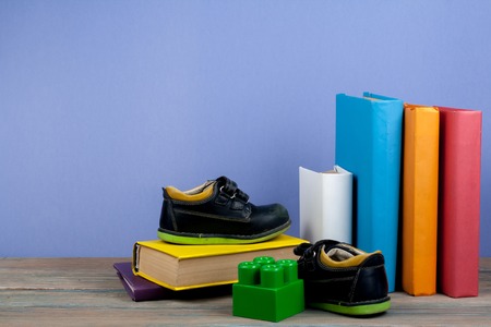 hardback colorful books, toy, shoes on wooden table. Back to school. Copy space for text. Education business concept.の写真素材