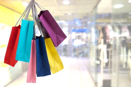 Crop female hand holding colorful paper bags on background of shopping center.の写真素材
