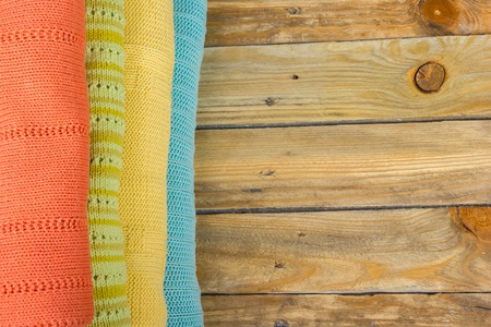 Knitted wool sweaters. Pile of knitted summer clothes on wooden background, sweaters, knitwear, space for text.の写真素材