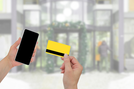 Man holding credit card in hand and entering security code using mobile phone.の写真素材