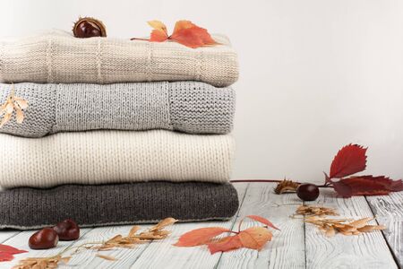 Knitted wool sweaters. Pile of knitted winter, autumn clothes on wooden background, sweaters, knitwear, space for text.の写真素材