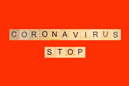 Coronavirus STOP word written on wood block, isolated on red background. top view.