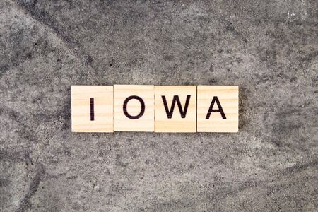 Iowa word written on wood block, on gray concrete background. Top view.の写真素材