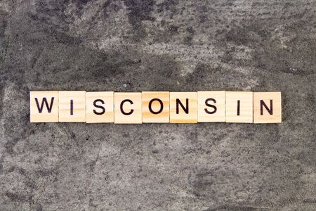 Wisconsin word written on wood block, on gray concrete background. Top view.の写真素材