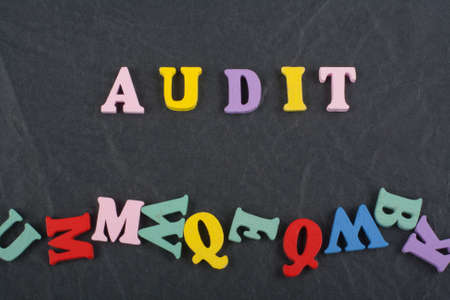 AUDIT word on black board background composed from colorful abc alphabet block wooden letters, copy space for ad text. Learning english concept.の写真素材