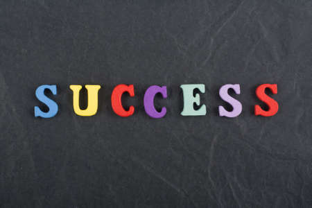 SUCCESS word on black board background composed from colorful abc alphabet block wooden letters, copy space for ad text. Learning english concept.の写真素材