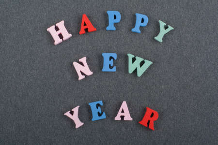 HAPPY NEW YEAR word on black board background composed from colorful abc alphabet block wooden letters, copy space for ad text. Learning english concept.の写真素材