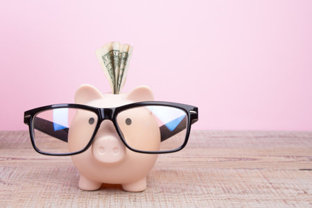 Piggy bank wearing a black glasses over pink backgroundの写真素材