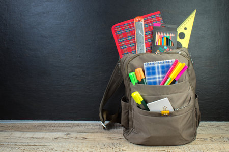 Backpack with different colorful stationery on table. Black background. back to schoolの写真素材