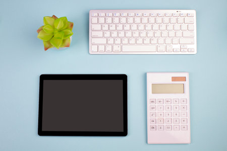 Tablet, calculator, phone, pen and a cup of coffee, lot of things on a blue background. top view with copy spaceの写真素材