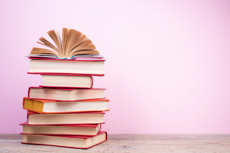 Composition with hardback books, fanned pages on wooden deck table and pink background. Book stacking. back to school. copyspace. education background. Tuition payment.の写真素材