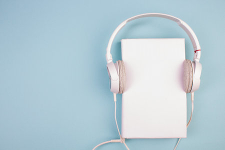 Headphones, mobile phone, idiobook, coffee cup on a blue background. The concept of leisure and learning, hobby. Listen to music, literature. Top view with copy space.の写真素材