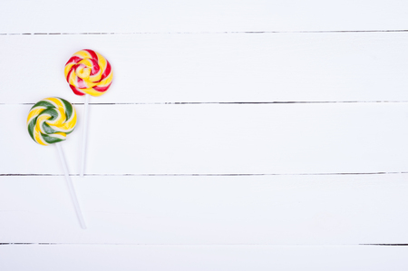 Colorful lollipops. Candies on white wooden background. Lots of copyspace. Top viewの写真素材
