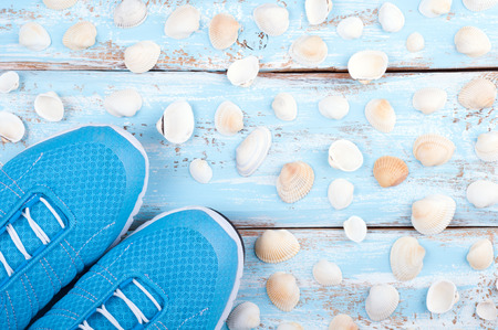 Sport shoes and sea shells on nautical wooden background. Top view sport equipment. Healthy life conceptの写真素材