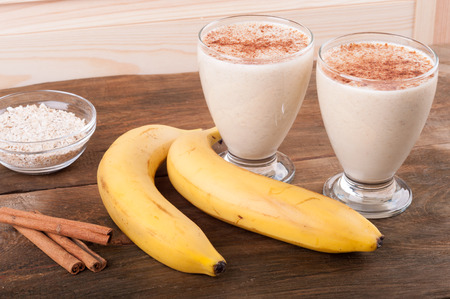 Fresh banana smoothie with oatmeal and cinnamon on wooden backgroundの写真素材