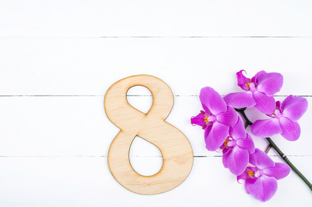 8 March International Women's Day background with copy space. 8 march greeting card with blooming orchid flowers on white wooden table. Rustic styleの写真素材
