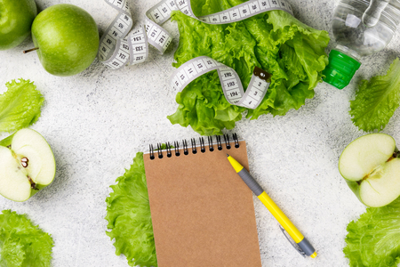 Healthy eating. Green apple, lettuce salad, water bottle, measuring tape. Dieting, slimming, weight loss and meal planning concept. Copy space and top viewの写真素材
