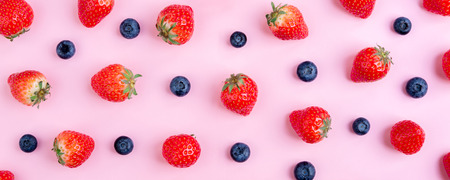 Strawberry and blueberry on pink background. Berries pattern, flat lay. Summer berry banner. Creative food conceptの写真素材