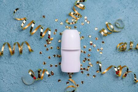 Flat lay composition with deodorant and golden confetti, streamers on blue background. Beauty, hygiene, cosmetics concept. Top viewの写真素材