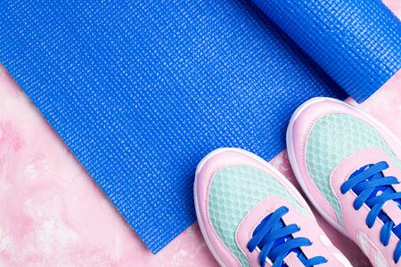 Blue yoga mat, sport shoes on pink background. Concept healthy lifestyle, sport life, fitness and diet. Sport equipment. Copy space
の写真素材