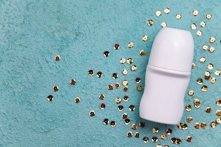 Flat lay composition with deodorant and golden confetti on blue background. Beauty, hygiene,...