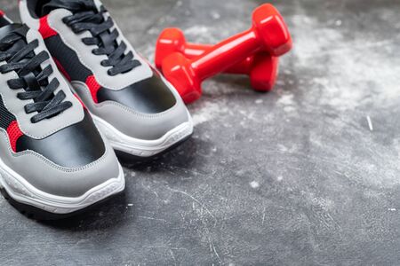 Sport shoes and red dumbbells on grey background. Concept healthy lifestyle, run, active, sport and diet. Sport equipment. Copy space
の写真素材