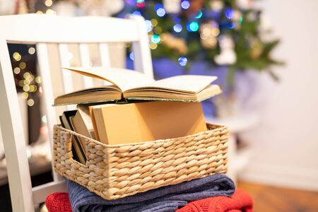 Warm sweaters, books and open book on festive bokeh background. Reading, cozy home, holidays conceptの写真素材
