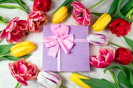 Festive background with flowers and gift box. Tulips and present on stone background. Holidays, Easter, happy birthday, anniwarsary, wedding, mother's day, congratulations card concept. Flat layの写真素材