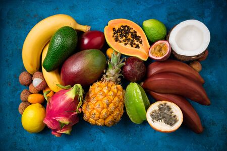 Summer tropical background with exotic various fruits on blue. Fruits background. Top viewの写真素材
