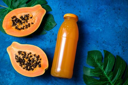Summer tropical background with exotic juice papaya, green palm leaves on blue. Summer drink. Copy space, top viewの写真素材