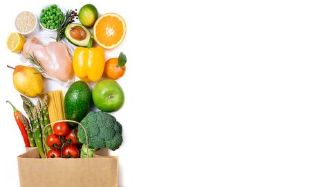 Healthy food background. Healthy food in paper bag meat, fruits, vegetables and pasta on white background. Shopping food in supermarket, dieting concept. Long format with copy spaceの写真素材