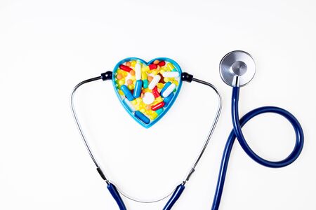 Stethoscope, pharmaceutical medicine pills, tablets, capsules on white background. Medication, cardiology and heart protect concept. Top viewの写真素材