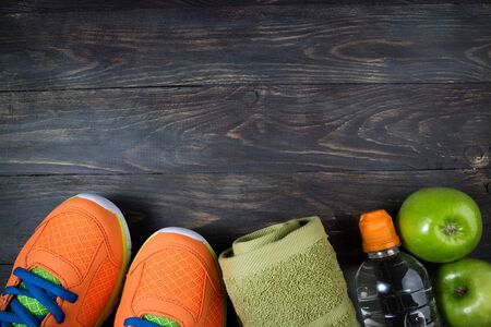 Sport shoes, apple, bottle of water and towel on wooden background. Concept healthy lifestyle, healthy food, sport and diet. Sport equipment. Top view, copy spaceの写真素材
