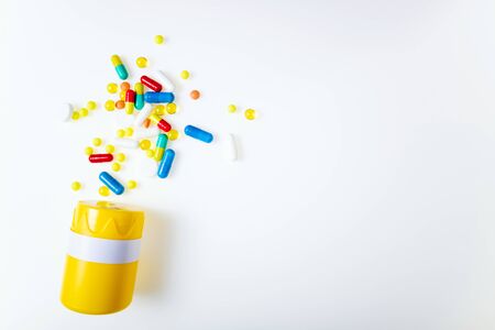 Pill bottle with assorted pharmaceutical medicine pills, tablets, capsules on white background top...
