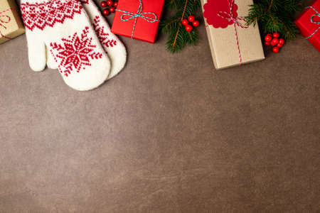 Christmas background with gift box, christmas tree, mittens and decorations on stone background. Top...