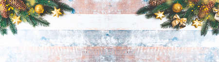 Festive Christmas border with fir branches, golden balls, pine cones and Christmas ornaments on old wooden background. Long format with copy spaceの写真素材