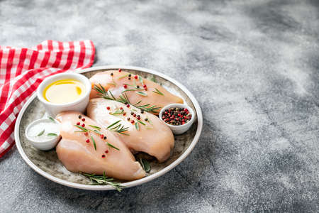 Chicken fillet with herbs and spices on gray table close up. Chicken meat with ingredients for cooking. Copy spaceの写真素材