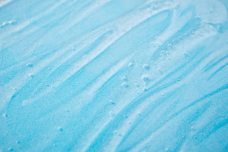 Liquid gel cosmetic on blue. Texture of liquid gel or sanitizer on blue background. Pattern of transparent gel for face cleansing. Moisturizing cosmetic beauty product for skincare. Lotion or serum for dry skin careの写真素材