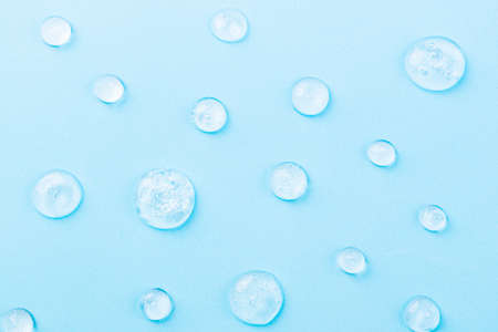 Liquid gel cosmetic on blue. Texture of gel on blue background. Pattern of transparent drops gel for...