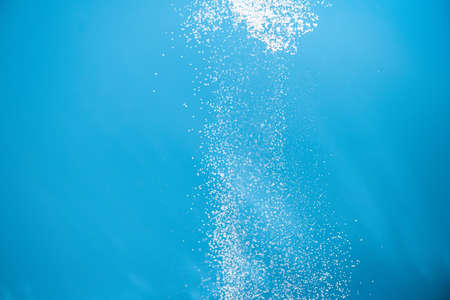 White powder splash isolated on blue background. Flour sifting on a blue background. Explosive powder whiteの写真素材