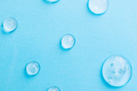 Cosmetics gel on blue. Pattern of blue gel drops or sanitizer. Background blue cosmetics gel for face cleansing. Moisturizing beauty product for skincare. Serum beauty product for skin careの写真素材
