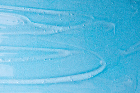 Cosmetics gel on blue. Texture of blue gel or sanitizer. Background blue cosmetics gel for face cleansing. Moisturizing beauty product for skincare. Lotion or serum beauty product for skin careの写真素材