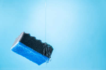 Kitchen dish washing sponge and dish washing liquid on blue background. Household cleaning scrub sponges with cleaning gel. Cleaning home concept. Copy spaceの写真素材