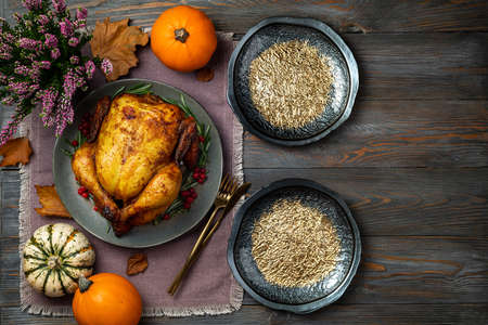 Festive table setting, roasted chicken or turkey for Thanksgiving Day on wooden table. Fried chicken, pumpkins for Thanksgiving dinner. Thanksgiving, Greetins, autumn concept. Copy spaceの写真素材