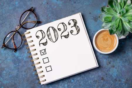 New year resolutions 2023 on desk. 2023 resolutions list with notebook, coffee cup on table. Goals, resolutions, plan, action, checklist concept. New Year 2023 template, copy spaceの写真素材