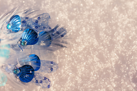 Blue and turquise christmas ornament of feathers and shells on the white shining snow background.の写真素材
