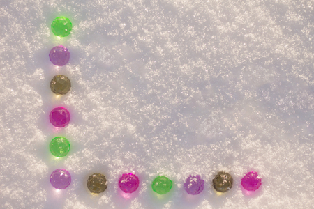 Many colorful christmas balls lined on the white shining snow background.の写真素材