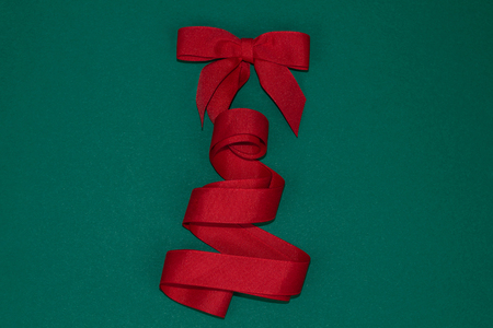 Beautiful Christmas tree with a bow made of silk red ribbon on green background.の写真素材