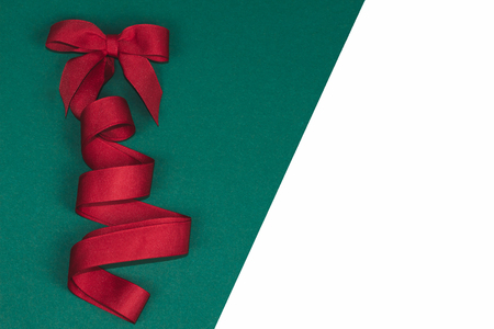 Beautiful Christmas tree with a bow made of silk red ribbon on green and isolated white background.の写真素材
