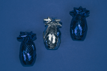 Christmas ornament of two blue and one silver shiny decorations shaped like pineapples lined on dark blue background.の写真素材